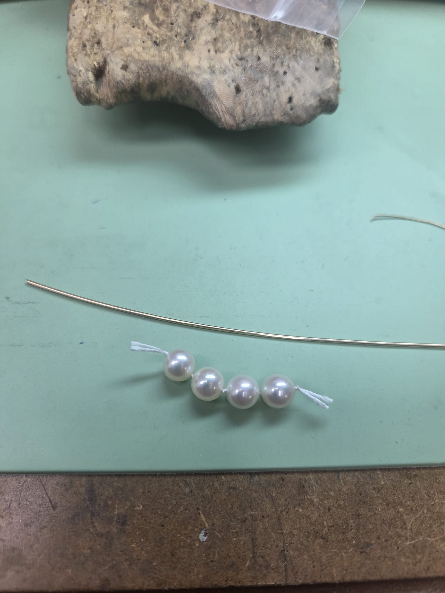 A strand of four pearls on a workshop desk