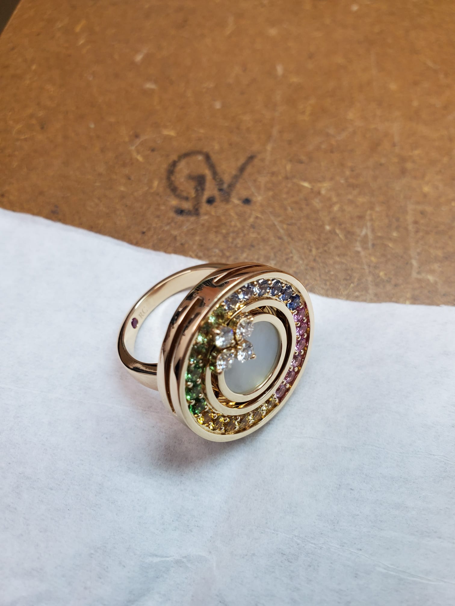 A gold ring set with rainbow gemstones angled to the right