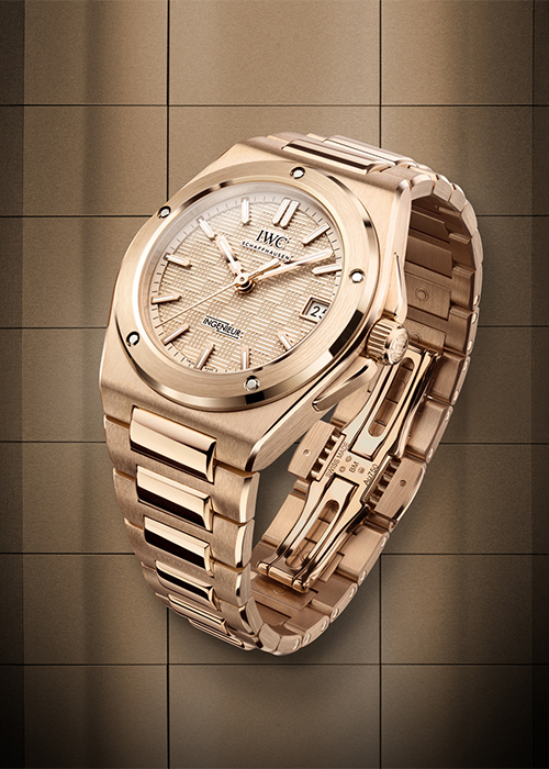 A gold IWC watch on a gold-tiled background