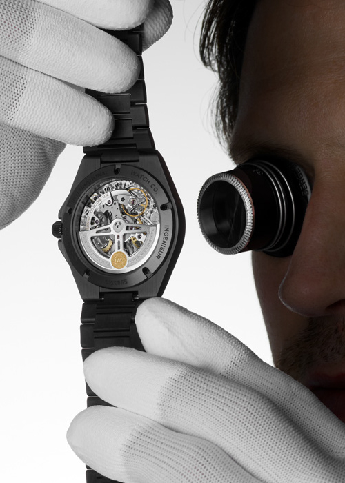 A watchmaker examining an IWC watch with a skeleton back